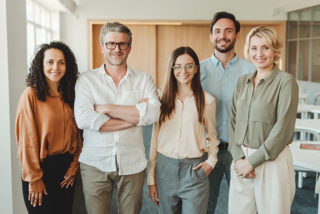 group of confident, smiling business people, colleagues, managers looking at camera in modern office